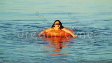 一位身穿泳装和眼镜的黑发女子在<strong>靠近</strong>海岸的海域游泳